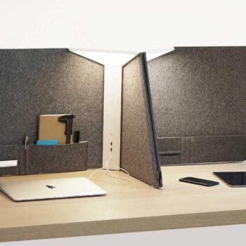 The Corner Office desk features a modern design with a partition, laptop, smartphone, tablet, and stationery. It's perfect for corner offices, equipped with built-in pockets and an overhead light to elevate your workspace.