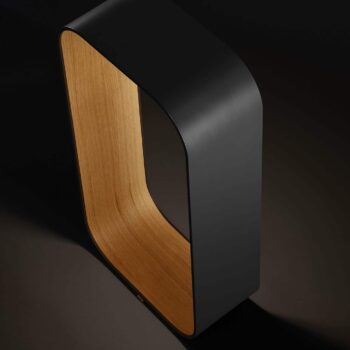 The Contour Floor lamp, with its sleek black exterior and wooden interior surface, embodies modern design. Its graceful curves are subtly illuminated from below against a dark background, making it a sophisticated addition to any space.