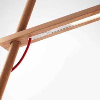 Close-up of Clamp lamp showcasing its linear light source and intersecting wooden beams with a red cord threading through.