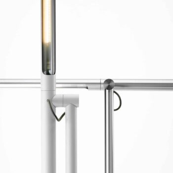 Close-up of the Brazo Floor, a modern, minimalist lighting fixture featuring cylindrical elements and a lit vertical tube connected by metal rods.