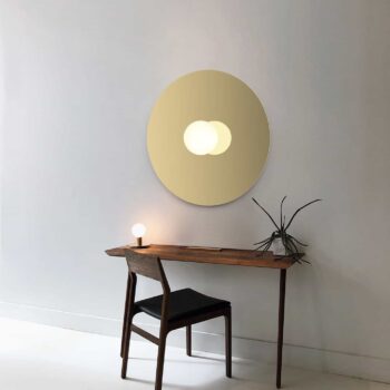 Bola Flush minimalist desk setup featuring a small lamp, chair, and plant, with a white wall and circular mirror.