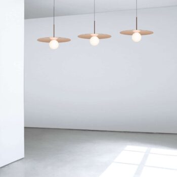 A Bola Disc Multi-Light Canopy with three pendant lights featuring round shades elegantly hangs in a minimalist, spacious room with a large window.