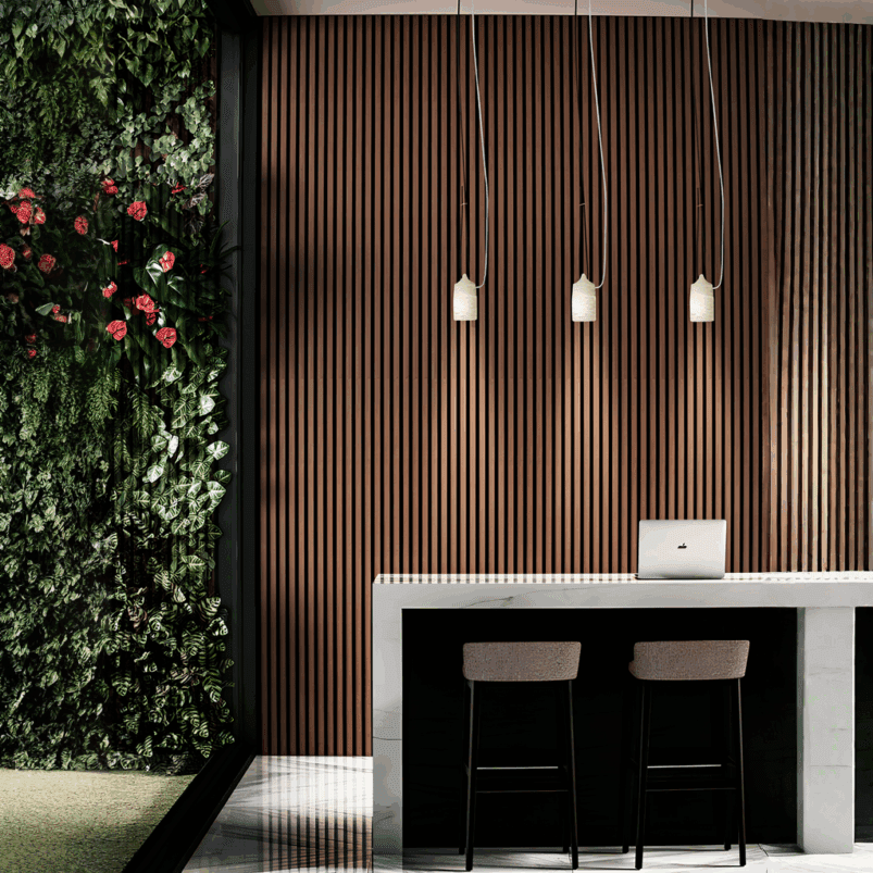 A modern workspace with a marble counter, two chairs, a laptop, warm ambience from three pendant lights, a wooden slat wall, and a vertical garden with green plants and pink flowers—perfect lighting for autumn.