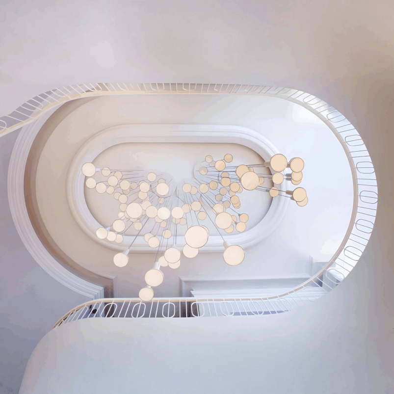 View looking up inside a white spiral staircase with modern circular light fixtures suspended in the center, creating a cozy ambience and perfect lighting for autumn evenings.