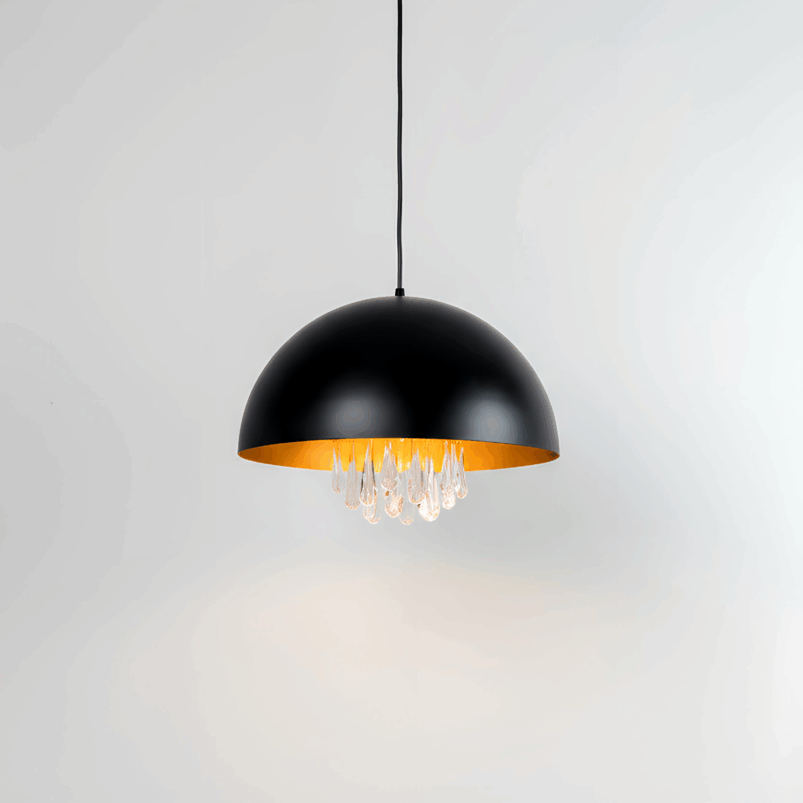 A modern pendant light with a black dome-shaped shade, gold interior, and hanging clear glass droplets creates a warm ambience, suspended from the ceiling against a plain white background.