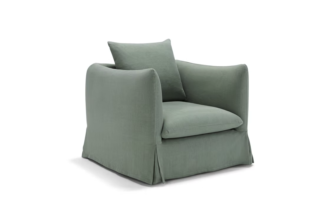 The Dylan Sofa is upholstered in sage green fabric with a matching cushion, featuring a skirted base and rounded armrests, displayed against a plain white background.