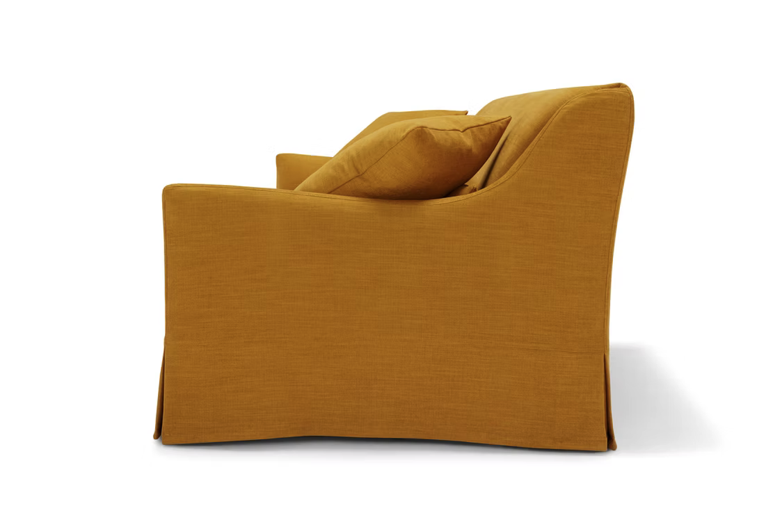 Side view of the Ralph Sofa in mustard yellow upholstery with a skirted base and two matching cushions, shown against a white background.