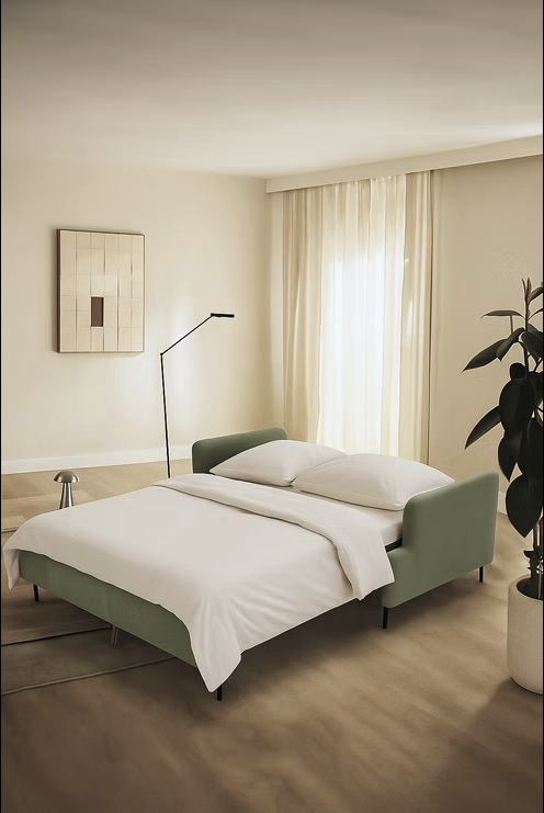 Minimalist bedroom with a green Tower Sofa-bed, white bedding, floor lamp, abstract wall art, sheer curtains, plant, and neutral-toned walls and flooring.